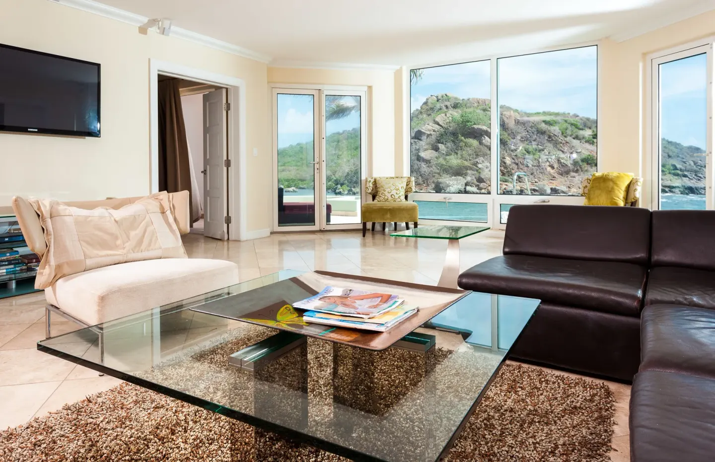 Living room with leather sofa and rocky shoreline views at Oyster Bay Beach Resort.