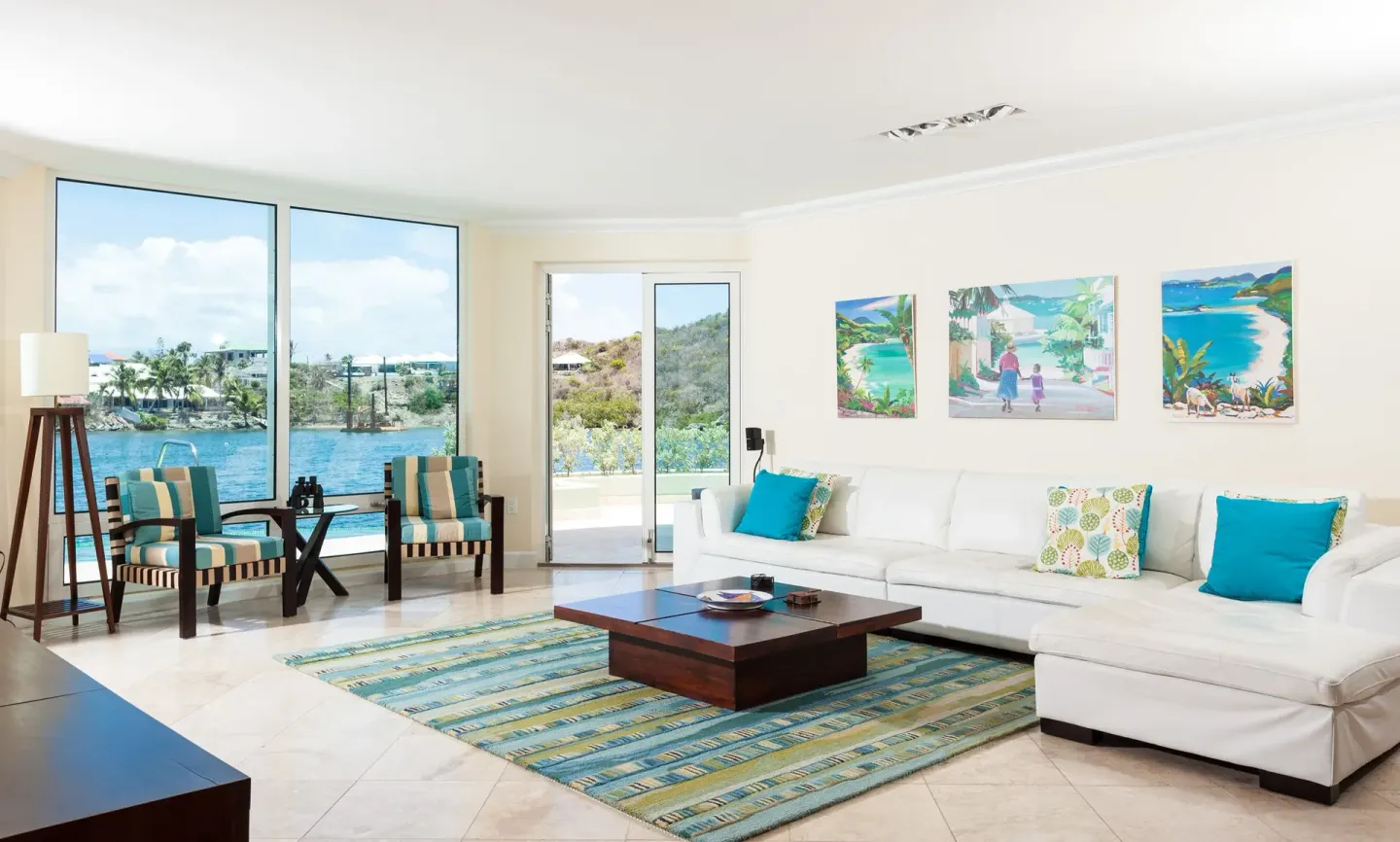 Bright living room with white sectional and water views at Oyster Bay Beach Resort.