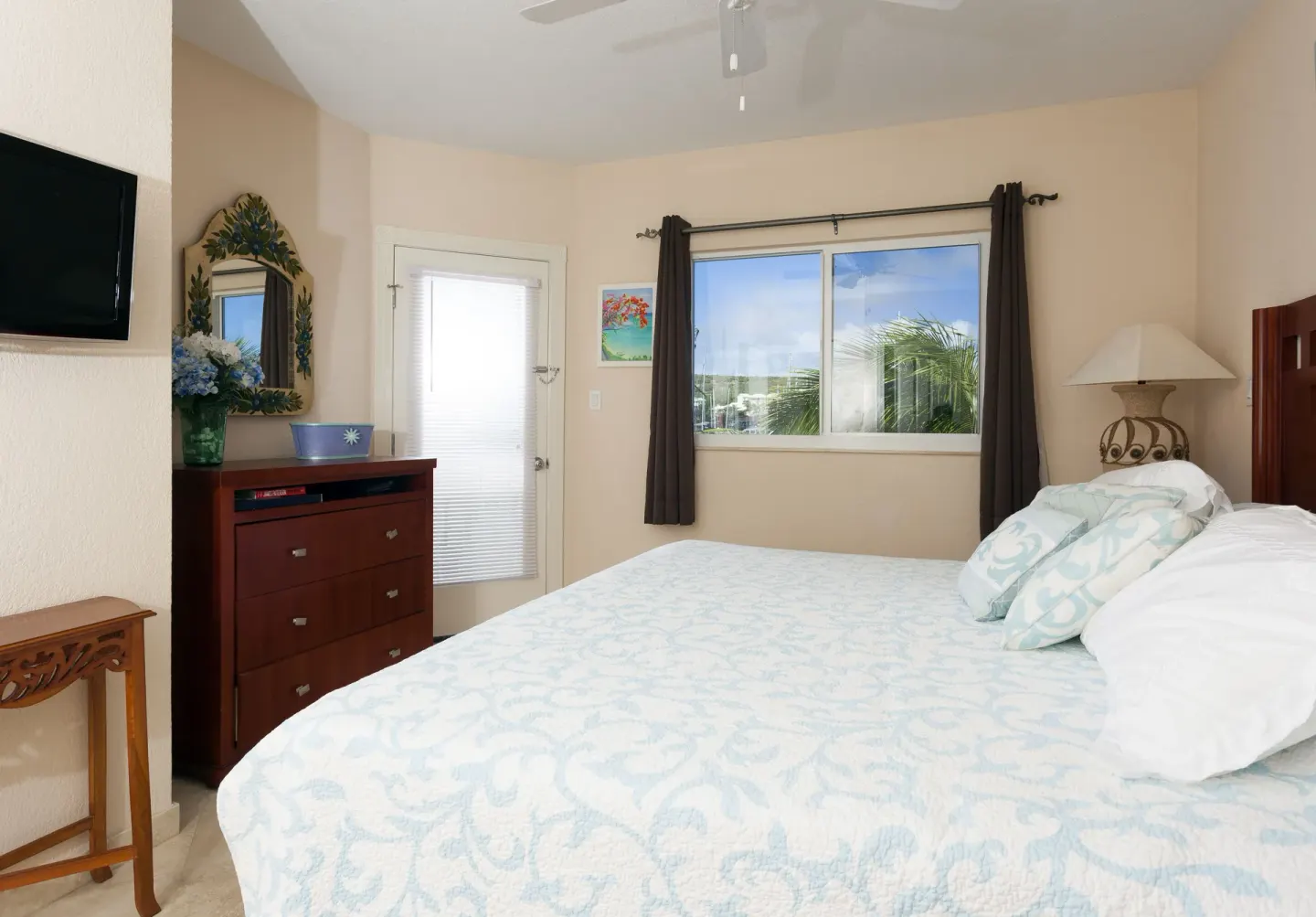Bedroom with king bed, dresser, mirror, and marina-facing window at Oyster Bay Beach Resort.