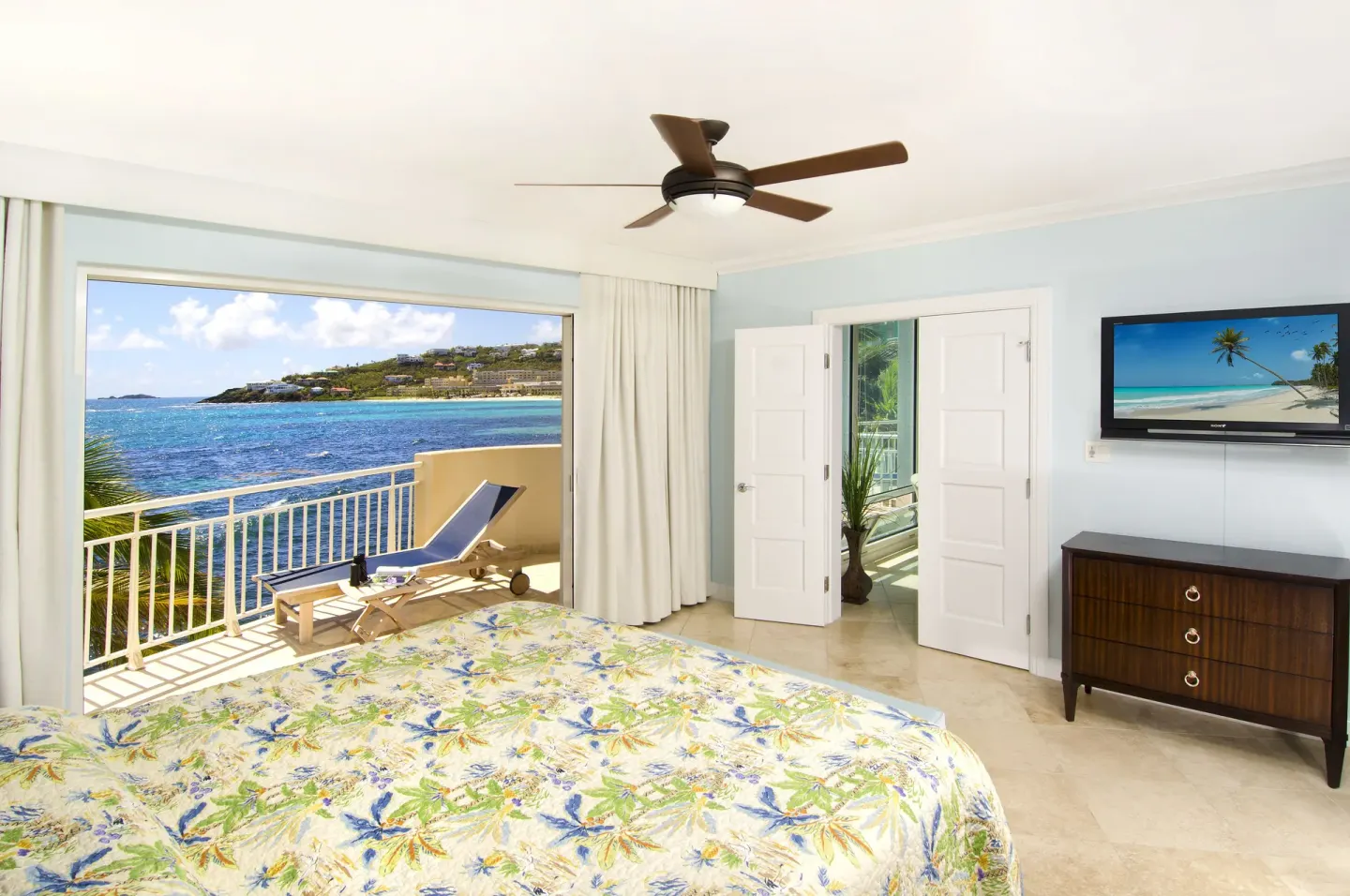 Ocean-view bedroom with king bed, TV, and balcony lounger at Oyster Bay Beach Resort.