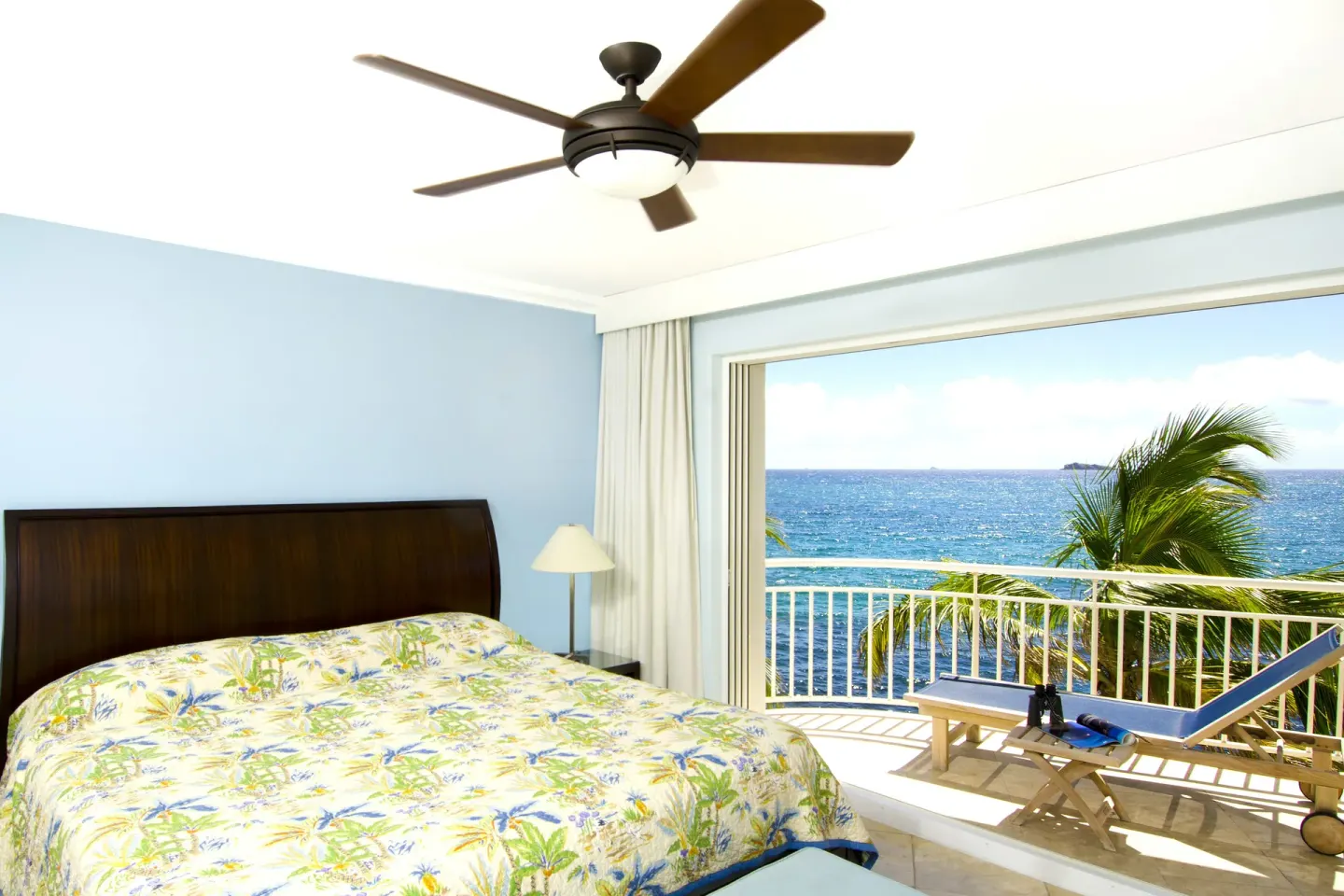 Guest room with king bed, balcony lounger, and ocean view at Oyster Bay Beach Resort.