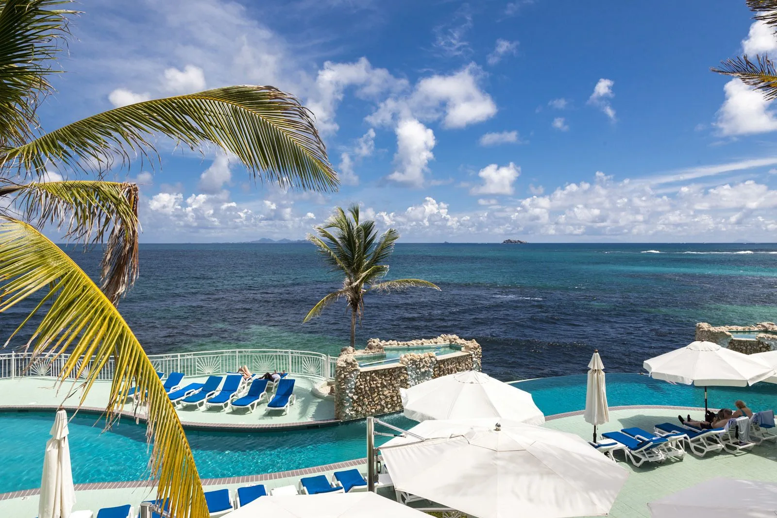 Oceanfront pool deck with loungers and umbrellas at Oyster Bay Beach Resort.
