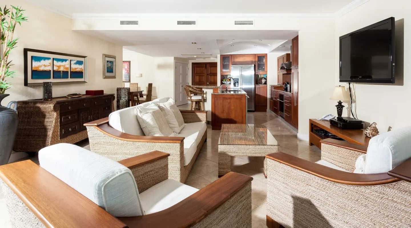 Living area with wicker seating and kitchen at Oyster Bay Beach Resort.