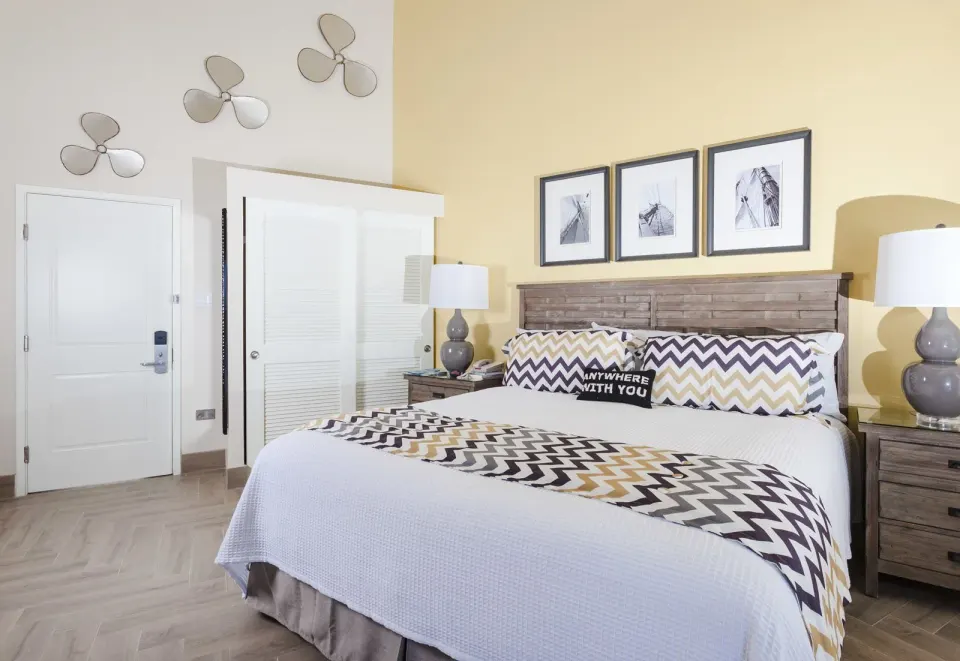 Deluxe Courtyard Loft king bed with entry door and wall art at Oyster Bay Beach Resort.