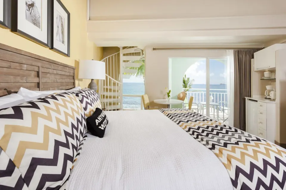 Deluxe Courtyard Loft king bed facing balcony and kitchenette at Oyster Bay Beach Resort.
