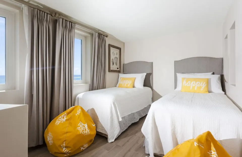Deluxe Courtyard Loft twin beds with ocean-facing windows at Oyster Bay Beach Resort.