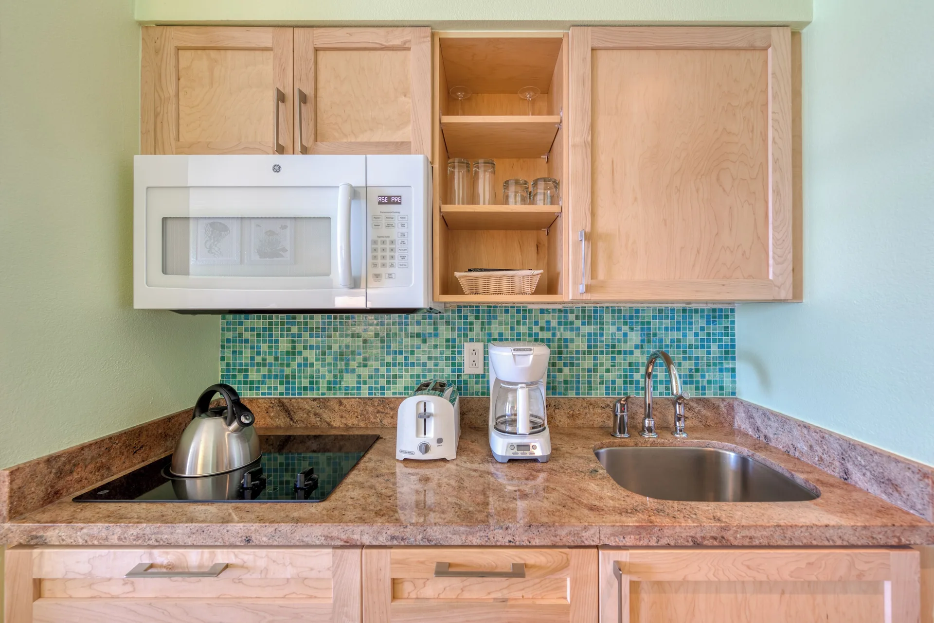 Studio kitchenette with microwave, sink, cooktop, and small appliances at Oyster Bay Beach Resort.