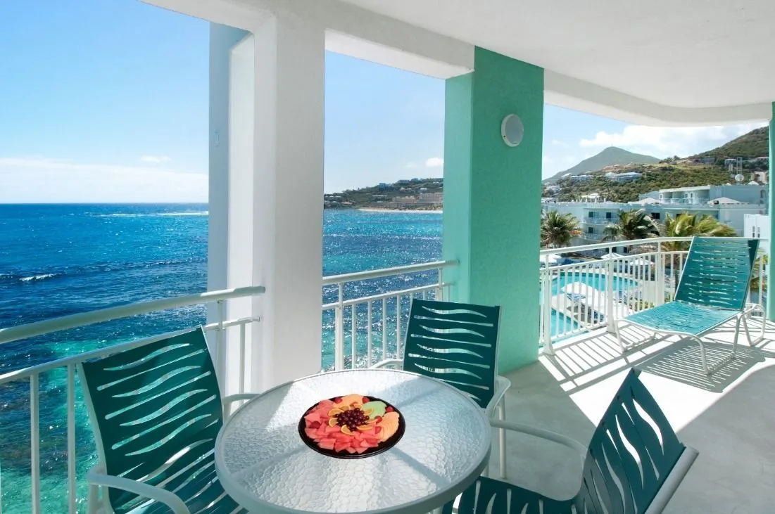 Oceanfront suite balcony with table, chairs and sea view at Oyster Bay Beach Resort.
