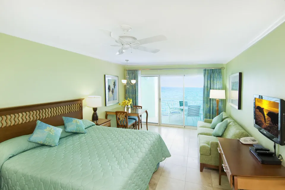Oceanfront suite bedroom with king bed, sofa and balcony doors at Oyster Bay Beach Resort.