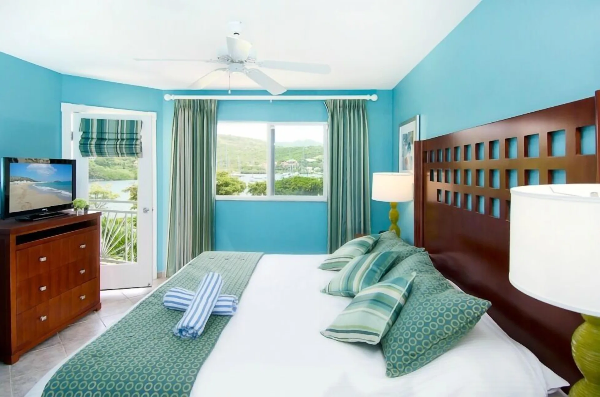 One-bedroom suite king bed with balcony and hillside view at Oyster Bay Beach Resort.