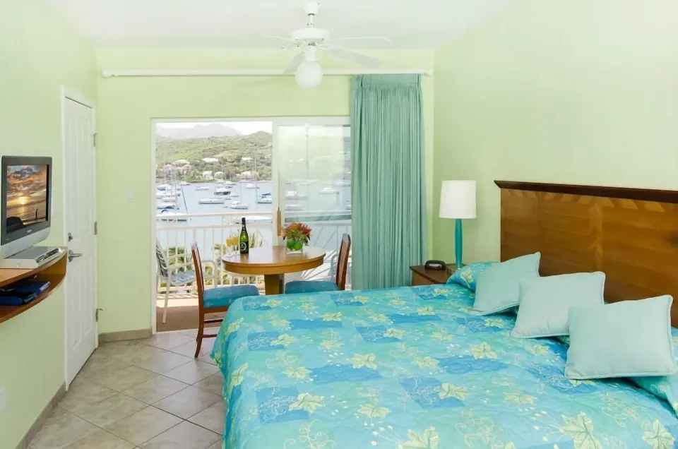 One-bedroom suite bed with balcony seating and marina view at Oyster Bay Beach Resort.
