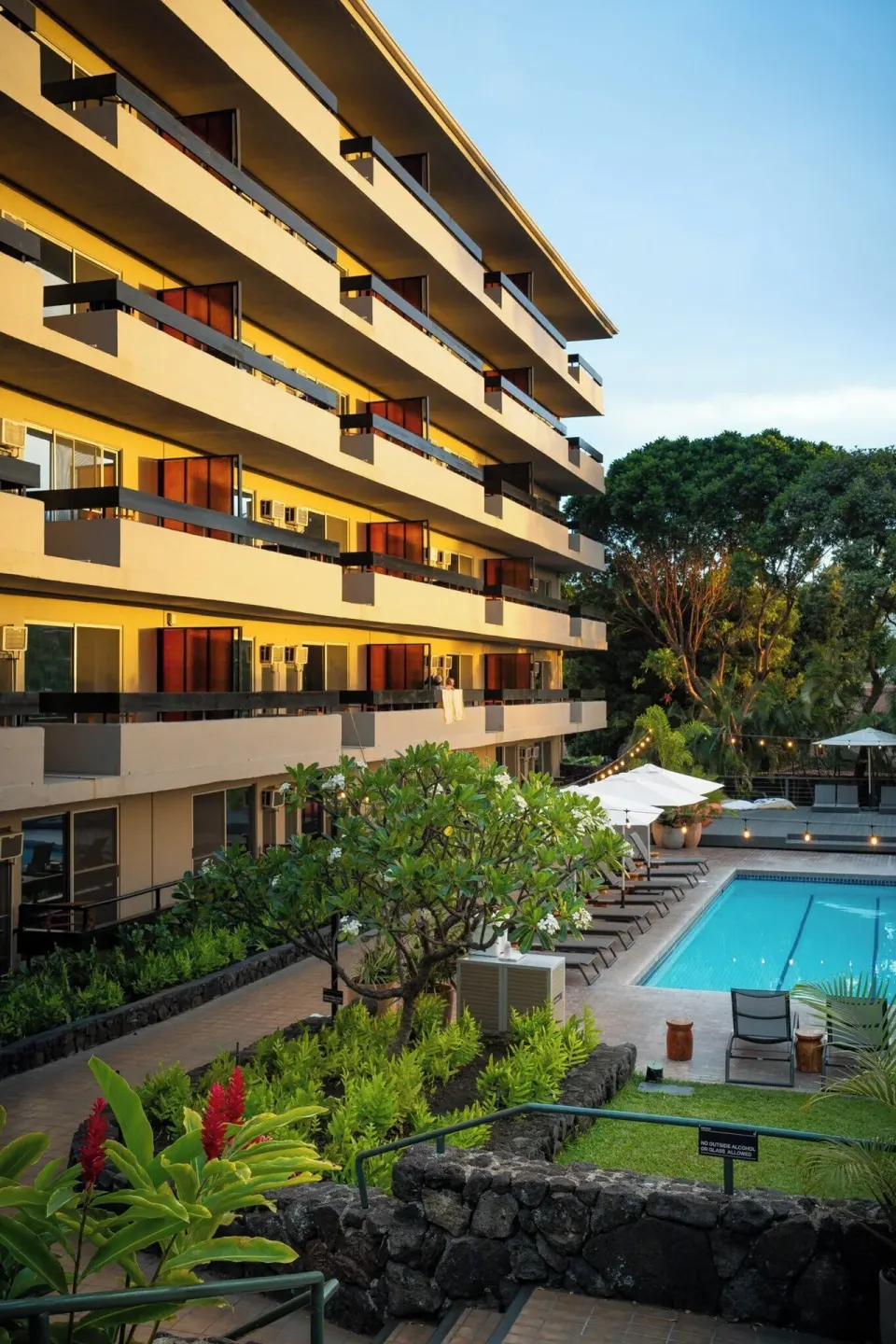 Resort building balconies overlook the pool and landscaped courtyard at PACIFIC 19 Kona.
