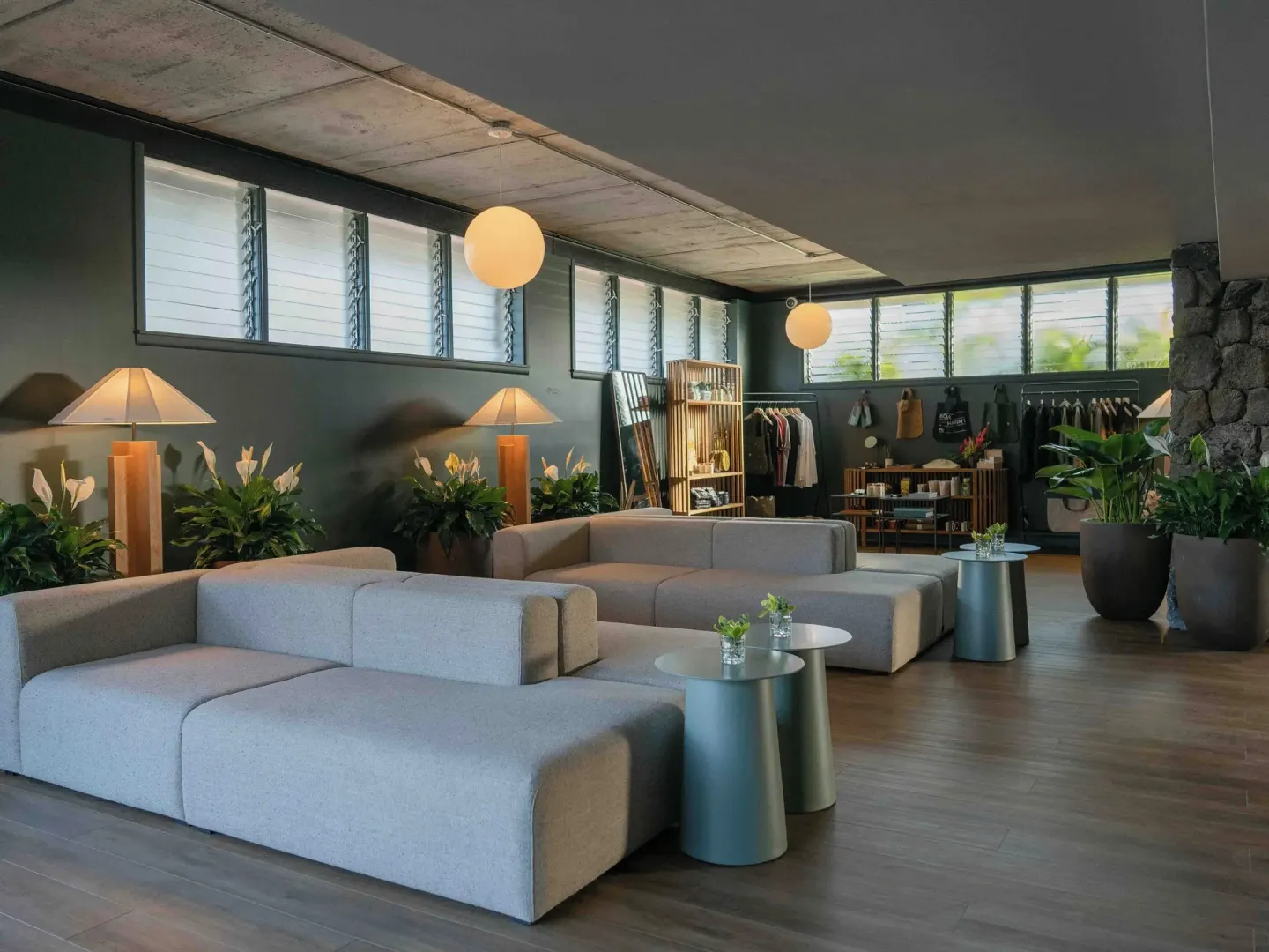 Lobby lounge sofas with small tables, globe lights, plants, and retail racks at PACIFIC 19 Kona.