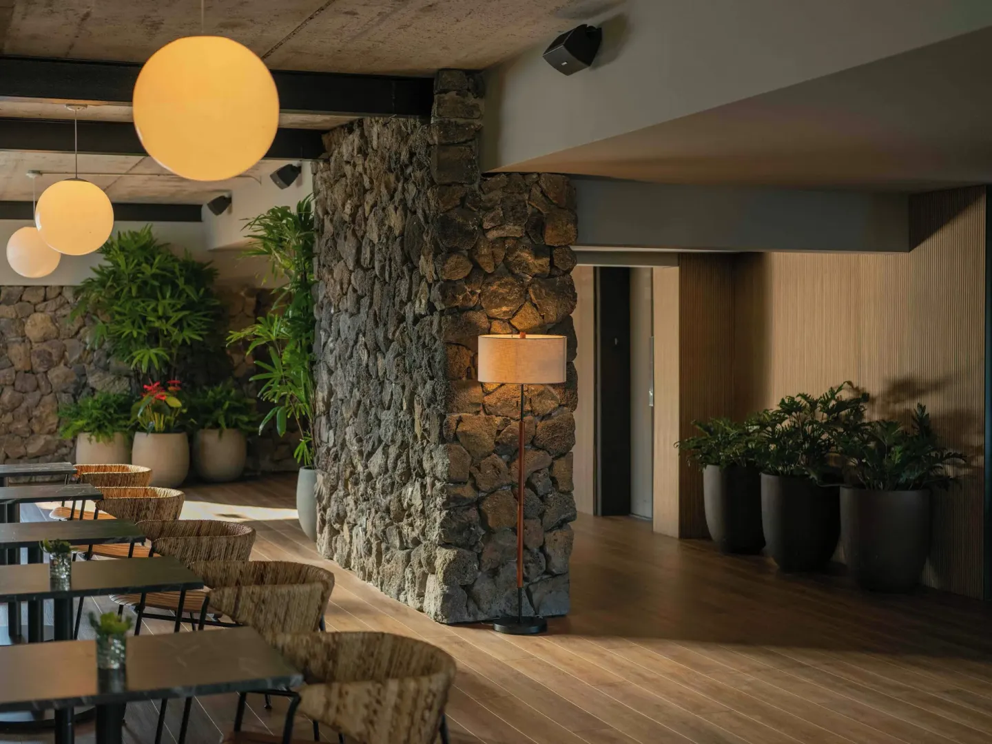 Lobby seating area with stone columns and globe lights at PACIFIC 19 Kona.