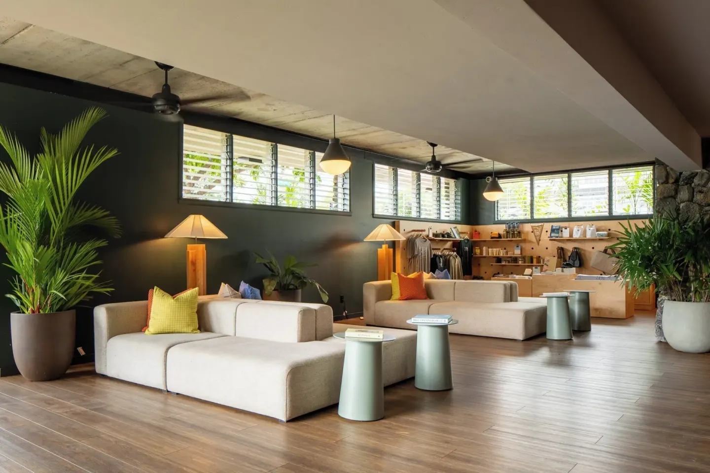 Open lobby seating area with sofas, plants, lamps, and display shelves at PACIFIC 19 Kona.