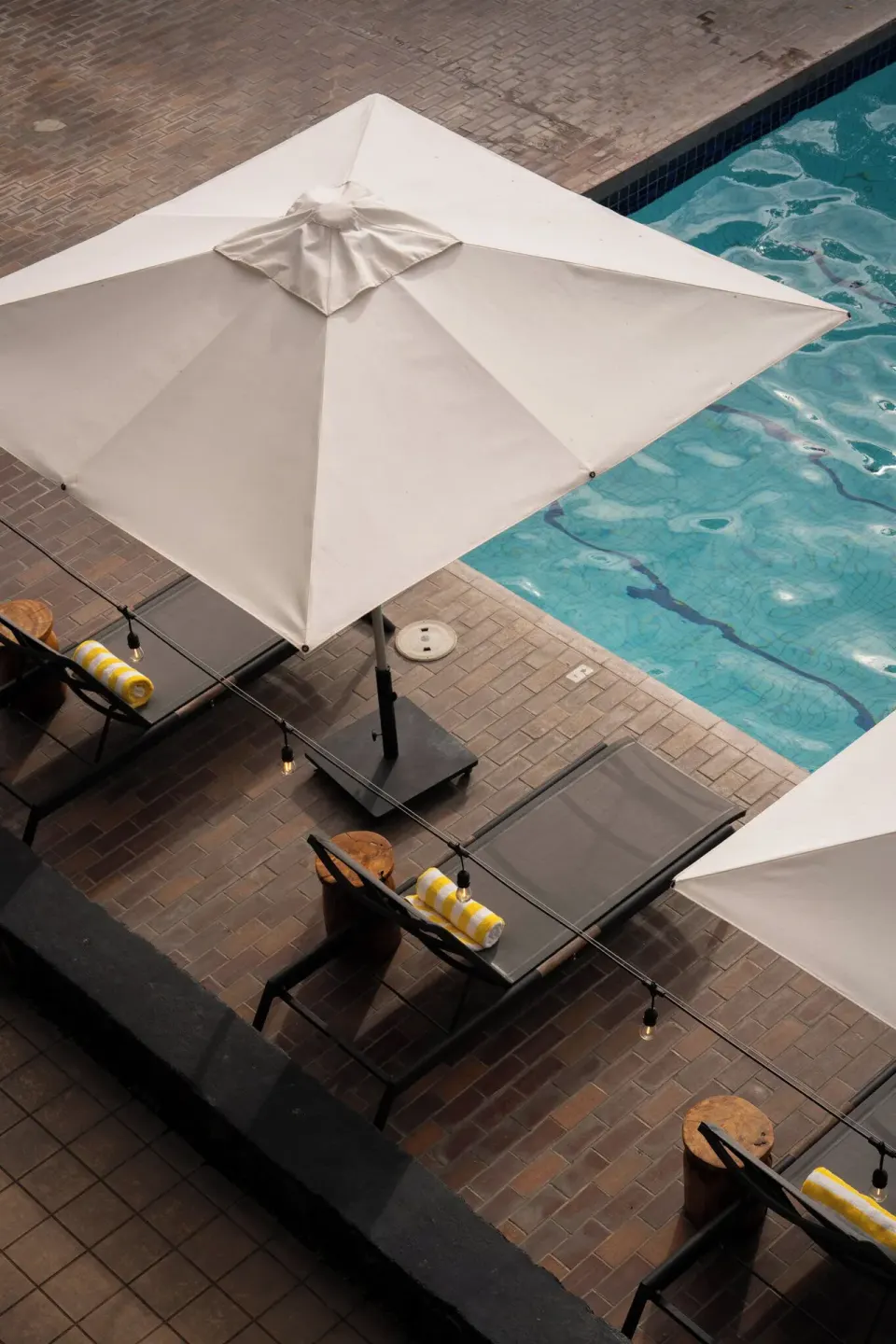 Overhead view of pool umbrellas, loungers, towels, and blue water at PACIFIC 19 Kona.