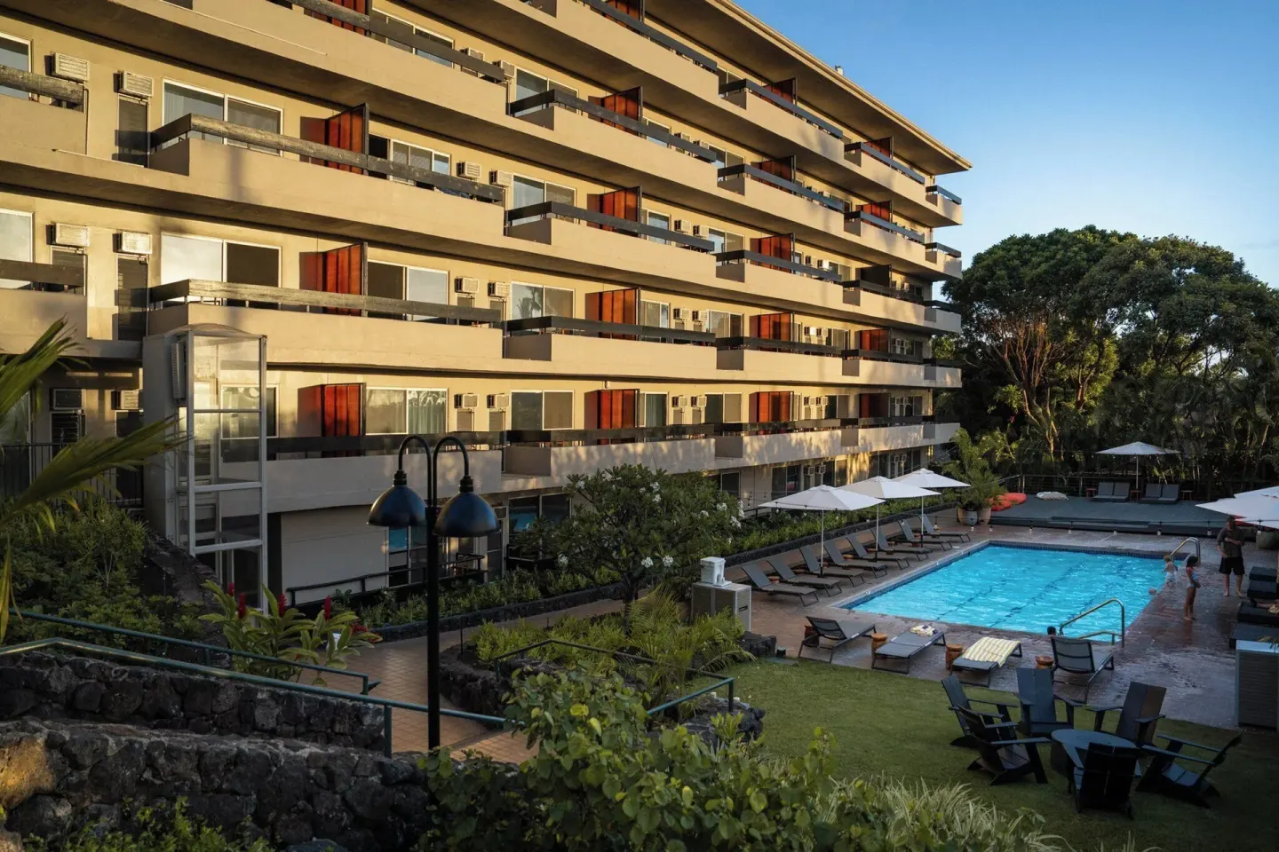 Hotel exterior, pool, loungers, umbrellas, and garden areas at PACIFIC 19 Kona.