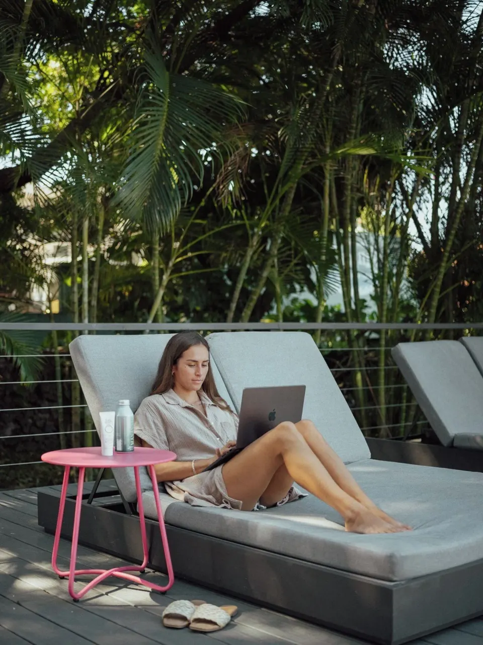 Guest relaxes with a laptop on a poolside lounge chair at PACIFIC 19 Kona.