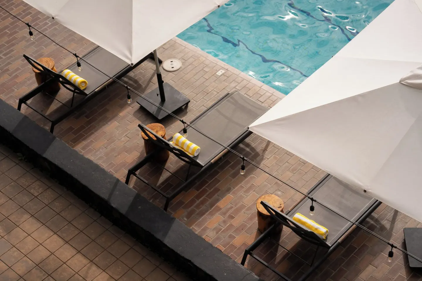 Angled overhead view of shaded loungers and pool water at PACIFIC 19 Kona.