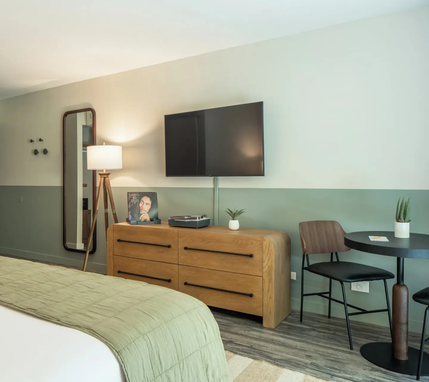 Apartment Suite bedroom corner with bed, dresser, TV, mirror and small table at PACIFIC 19 Kona.