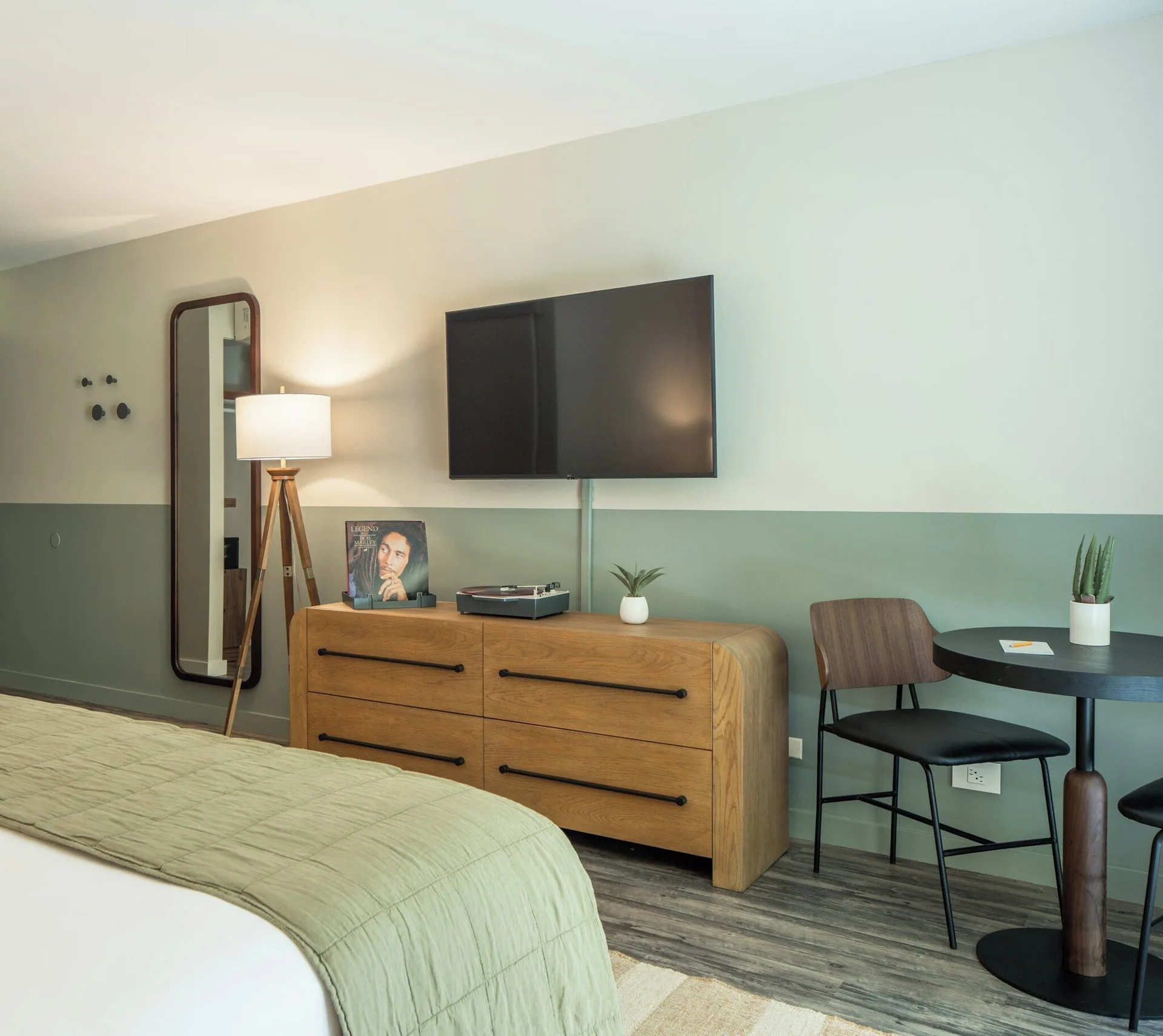 Apartment Suite bedroom corner with bed, dresser, TV, mirror and small table at PACIFIC 19 Kona.