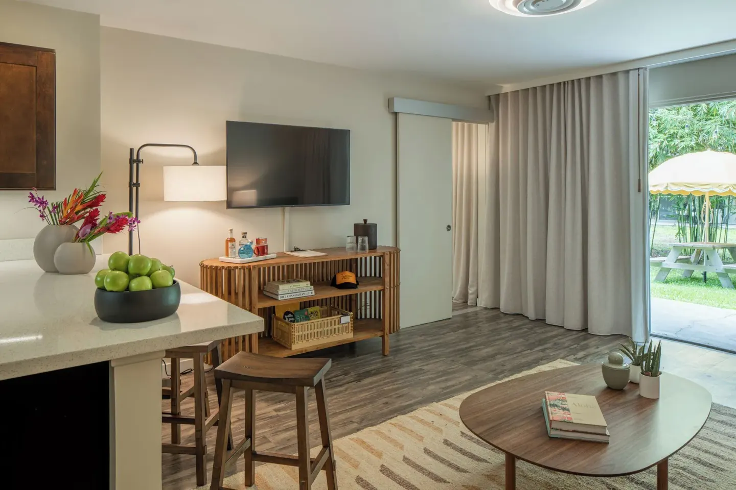 Apartment Suite living area with kitchenette, TV, patio door and lawn view at PACIFIC 19 Kona.