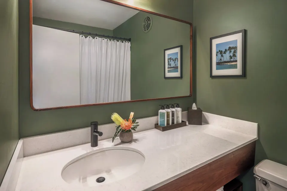 Pool View room bathroom vanity with large mirror and bath amenities at PACIFIC 19 Kona.