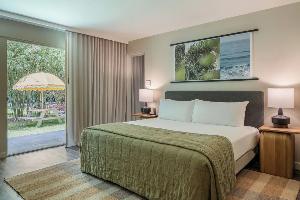 Suite Ohana king bed beside sliding patio door at PACIFIC 19 Kona.
