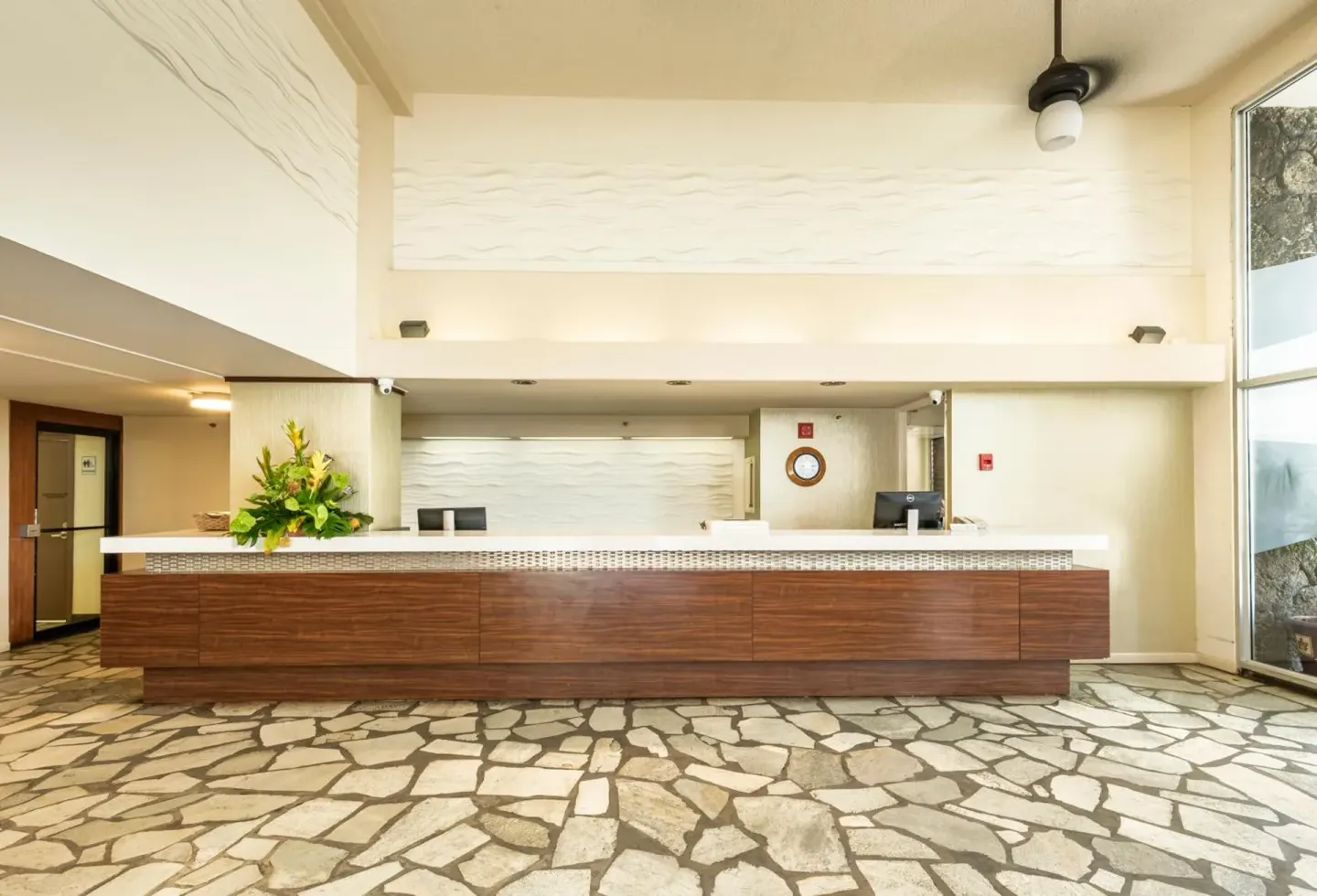 Front desk and stone-patterned lobby floor inside Pacific Monarch Hotel.