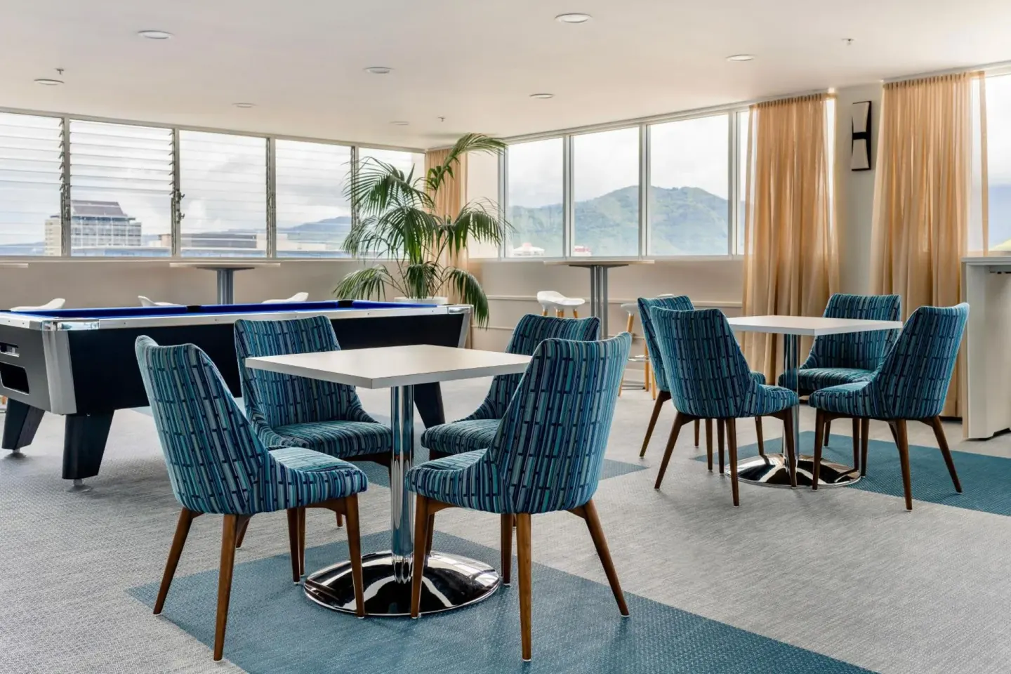 Game room with tables, chairs, and a pool table at Pacific Monarch Hotel.
