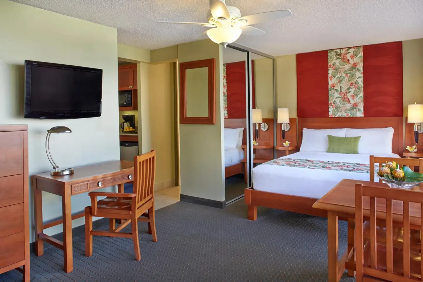 King-bed guest room with desk, dining table, and kitchenette at Pacific Monarch Hotel.