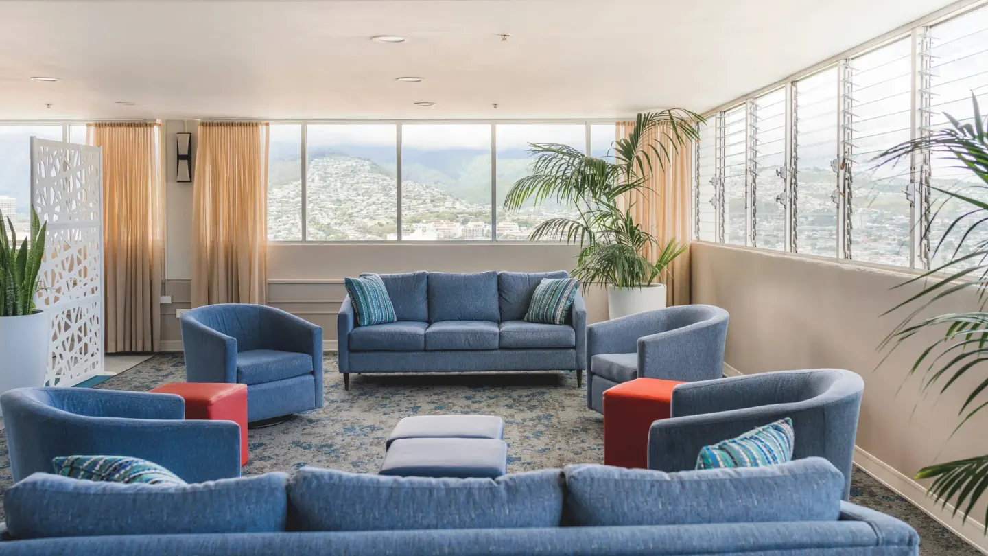 Indoor lounge with blue sofas and mountain views at Pacific Monarch Hotel.
