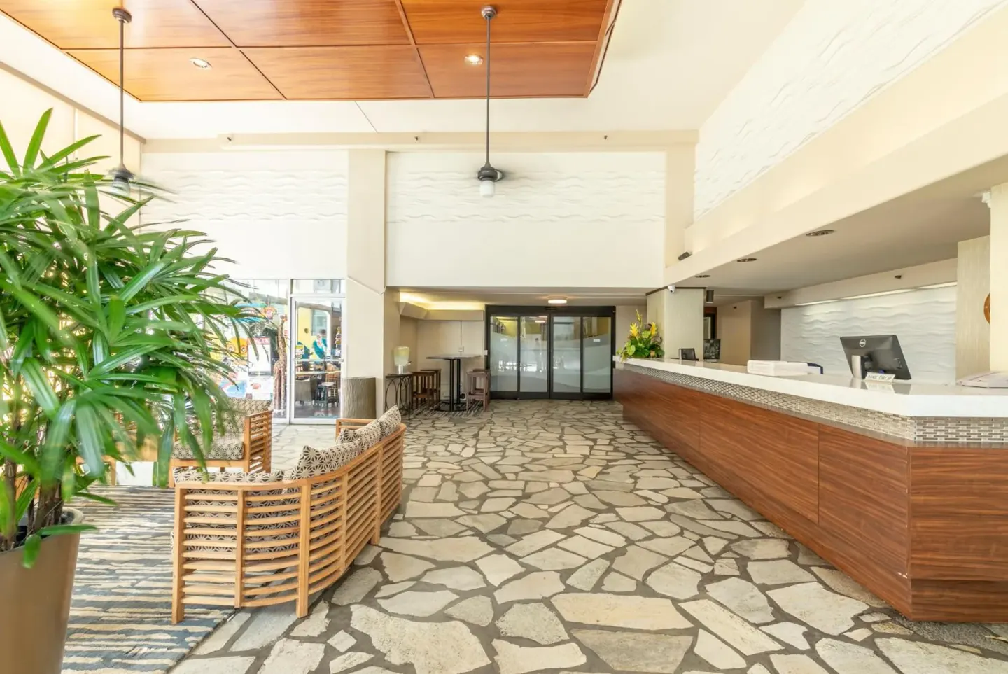 Lobby front desk and seating area with stone-patterned flooring at Pacific Monarch Hotel.
