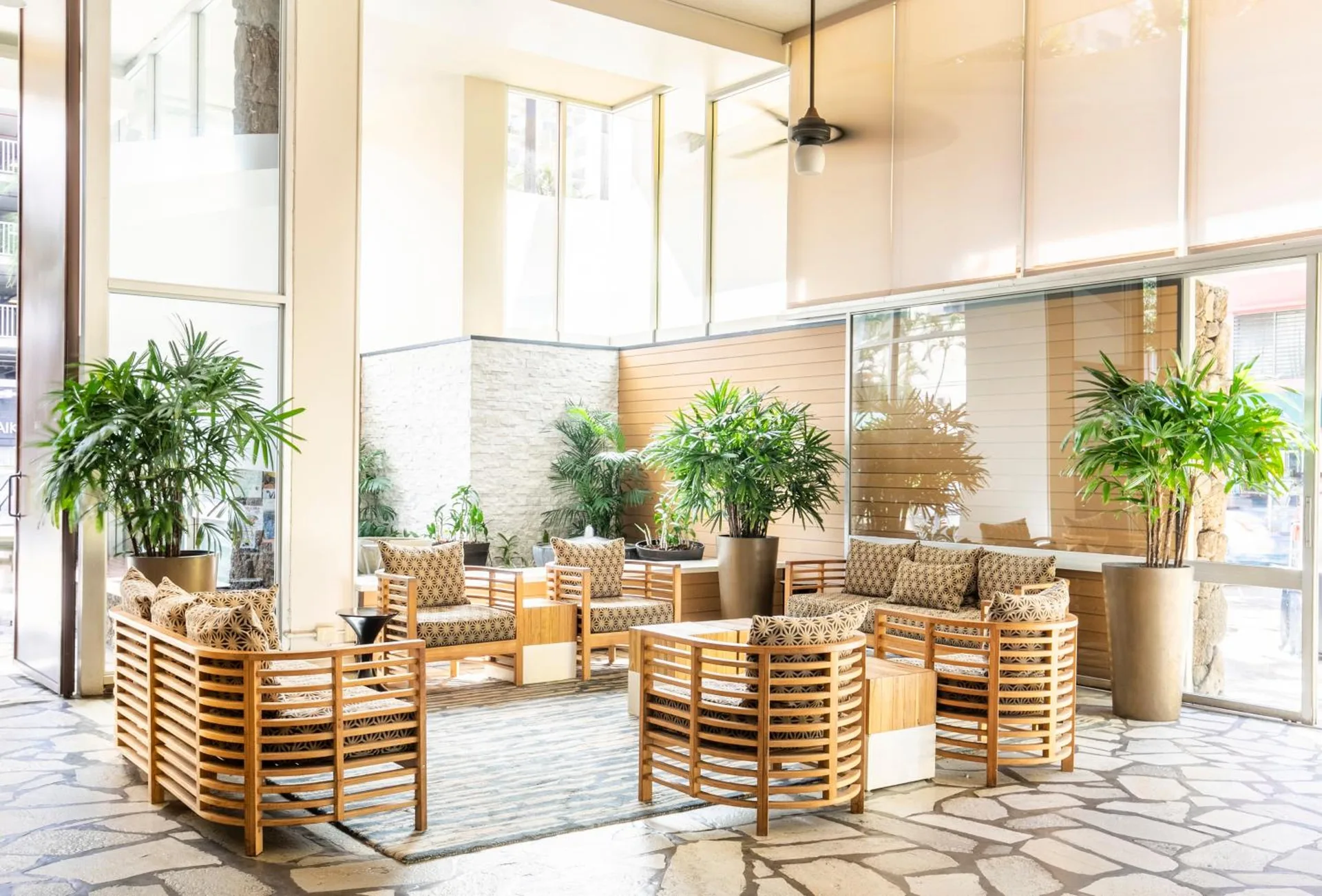 Lobby seating area with wood chairs and potted plants at Pacific Monarch Hotel.
