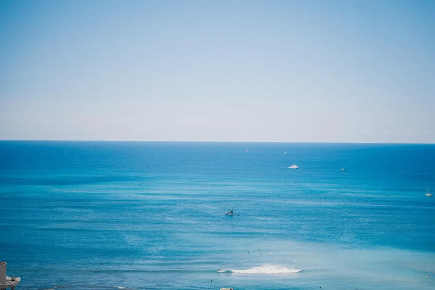 Wide blue ocean view with boats offshore from Pacific Monarch Hotel.