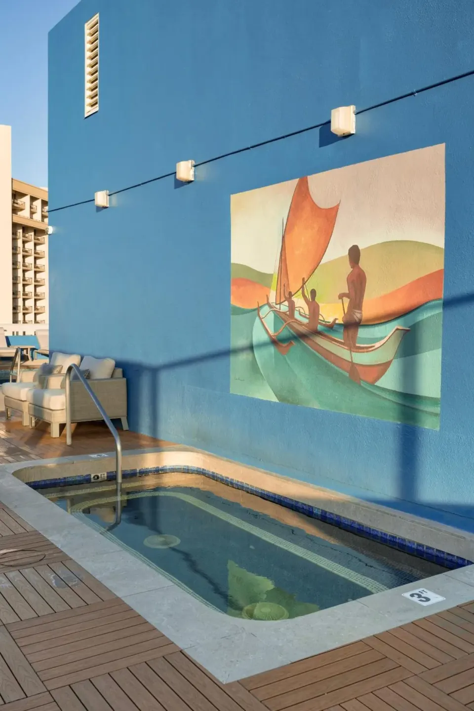 Rooftop hot tub beside a blue mural wall at Pacific Monarch Hotel.