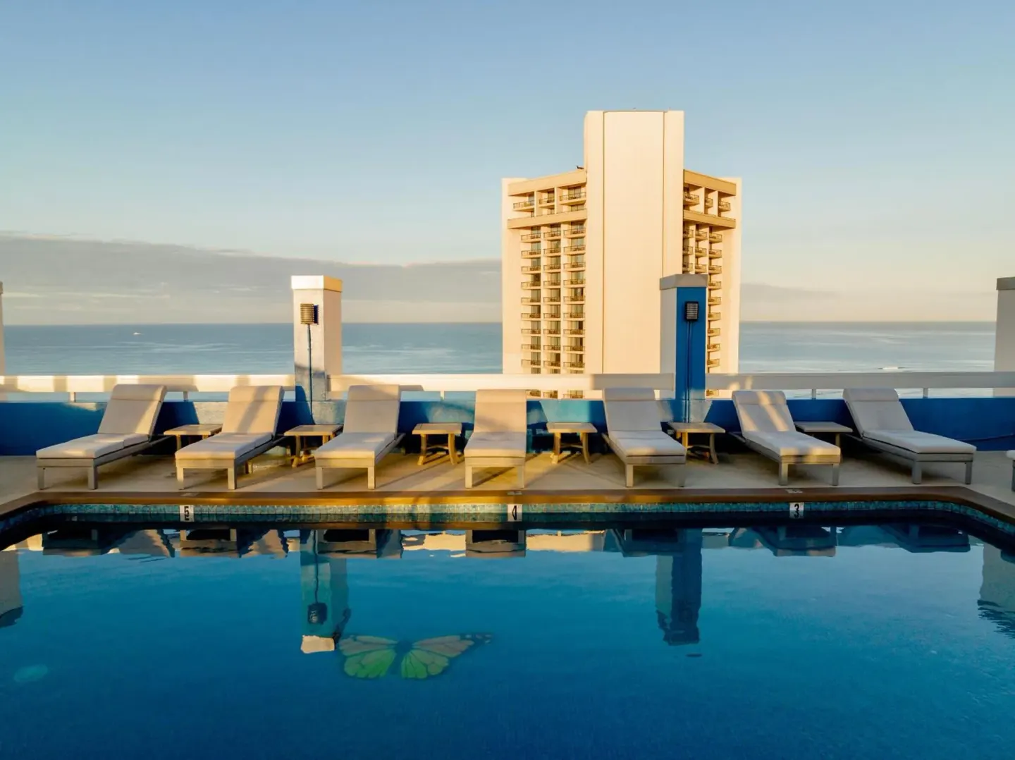 Rooftop pool with lounge chairs and ocean view at Pacific Monarch Hotel.