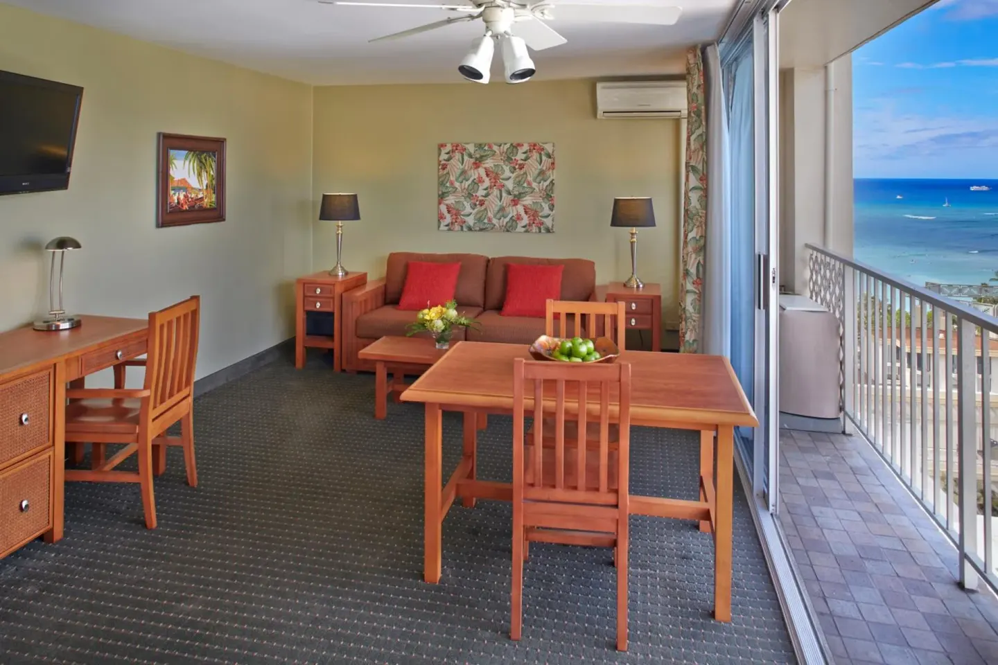 Living area with dining table, sofa, balcony, and ocean view at Pacific Monarch Hotel.
