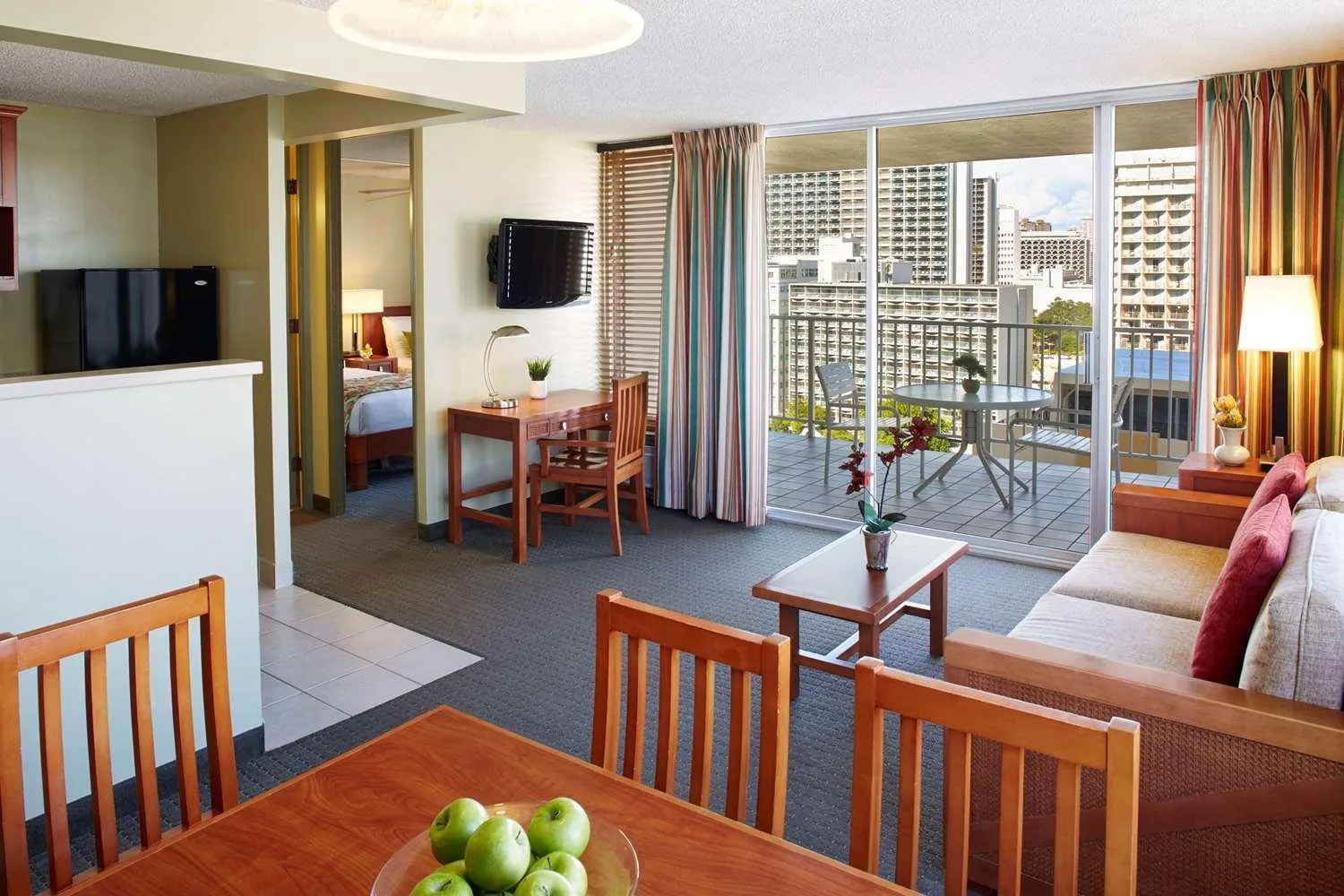 Suite living room with balcony, kitchenette, and dining area at Pacific Monarch Hotel.