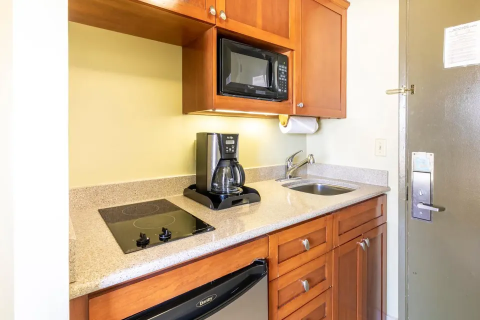Studio kitchenette with cooktop, microwave, sink, and coffee maker at Pacific Monarch Hotel.