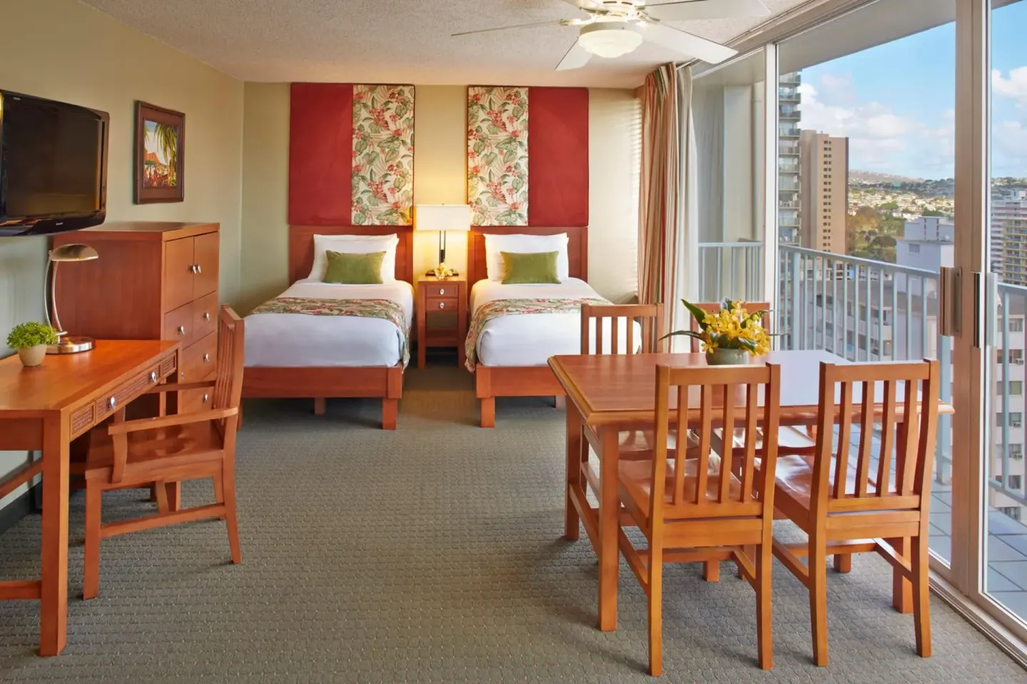 Studio with two beds, dining table, desk, and balcony windows at Pacific Monarch Hotel.