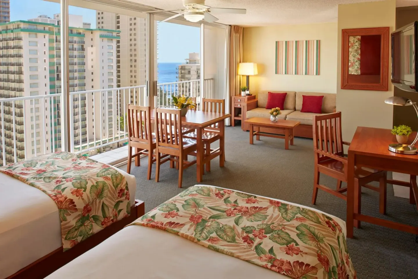 Studio with two beds, dining area, sofa, and partial ocean view at Pacific Monarch Hotel.