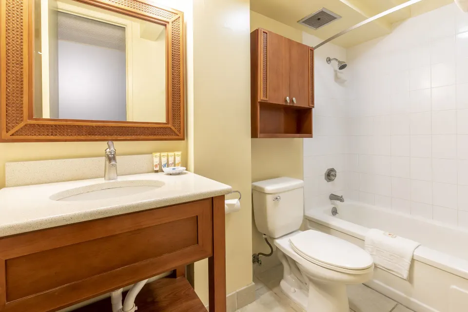 Studio Suite bathroom with vanity, toilet, tub, shower, and wall cabinet at Pacific Monarch Hotel.