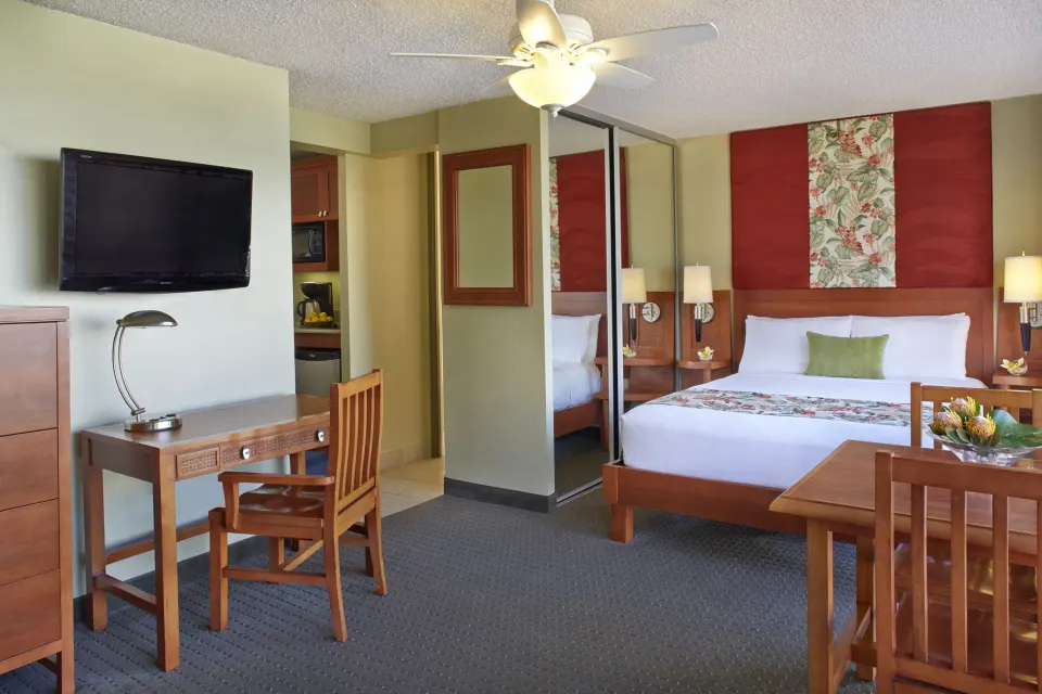 Studio suite with king bed, desk, TV, mirrored closet, and kitchenette entry at Pacific Monarch Hotel.