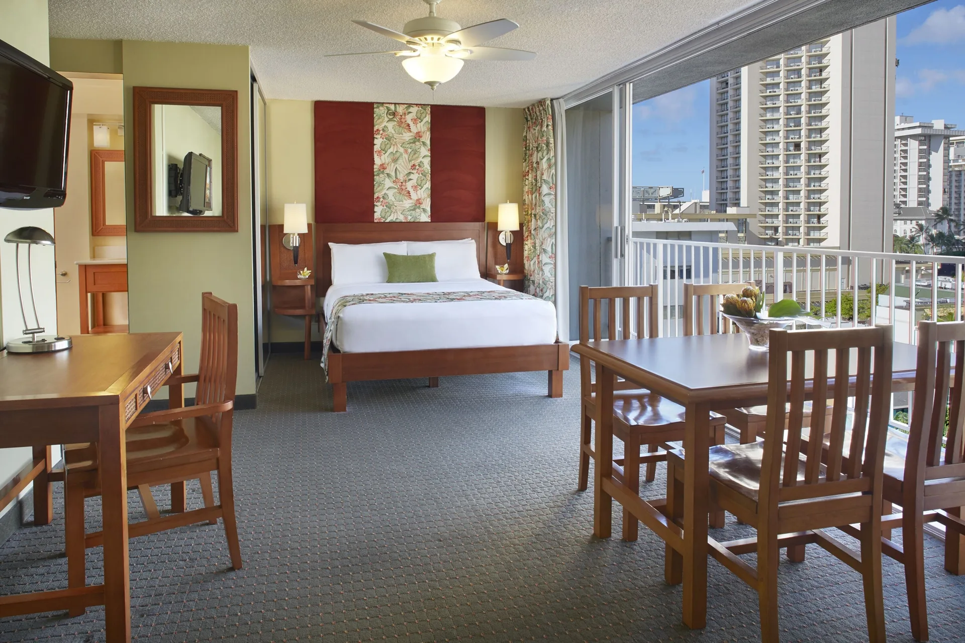 Studio suite with king bed, dining table, desk, and balcony windows at Pacific Monarch Hotel.