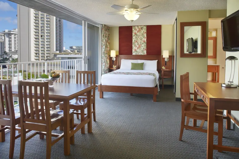 Studio suite with king bed, dining table, desk, and city-facing windows at Pacific Monarch Hotel.
