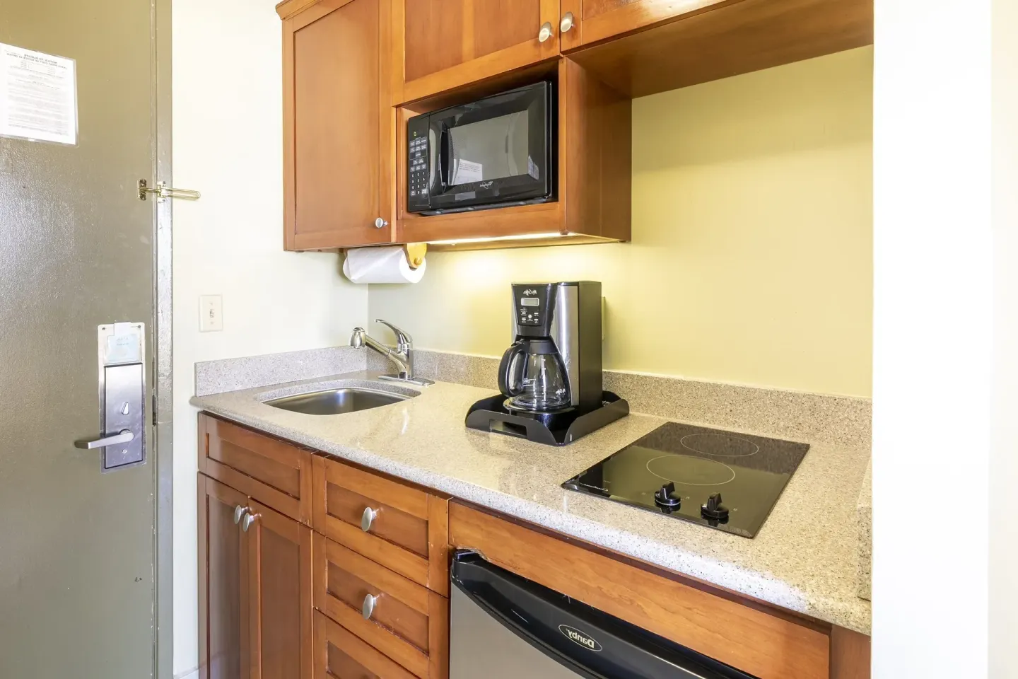 Studio suite kitchenette with sink, microwave, coffee maker, cooktop, and mini fridge at Pacific Monarch Hotel.