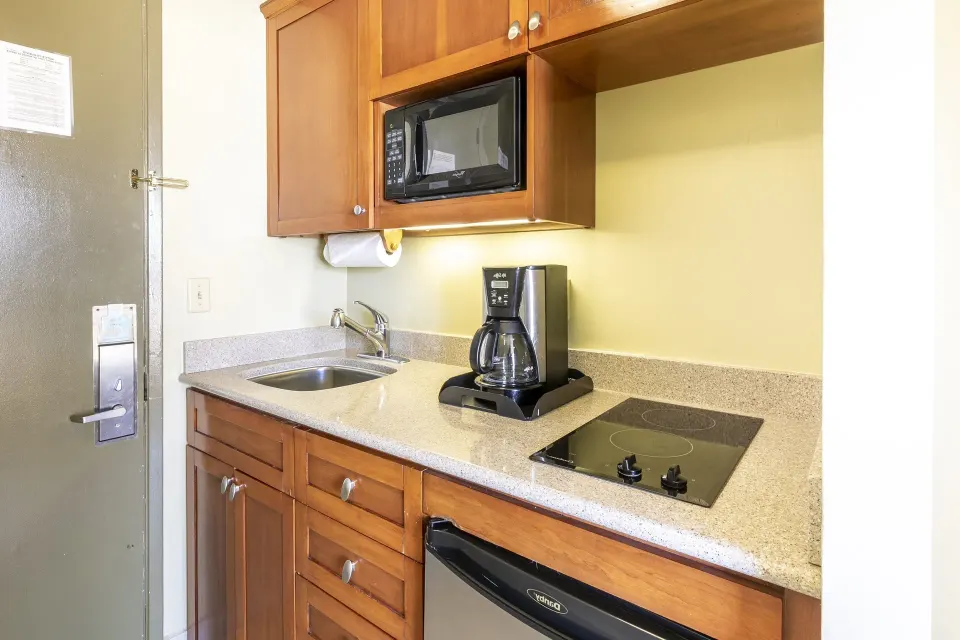 Studio suite kitchenette with sink, microwave, coffee maker, cooktop, and mini fridge at Pacific Monarch Hotel.