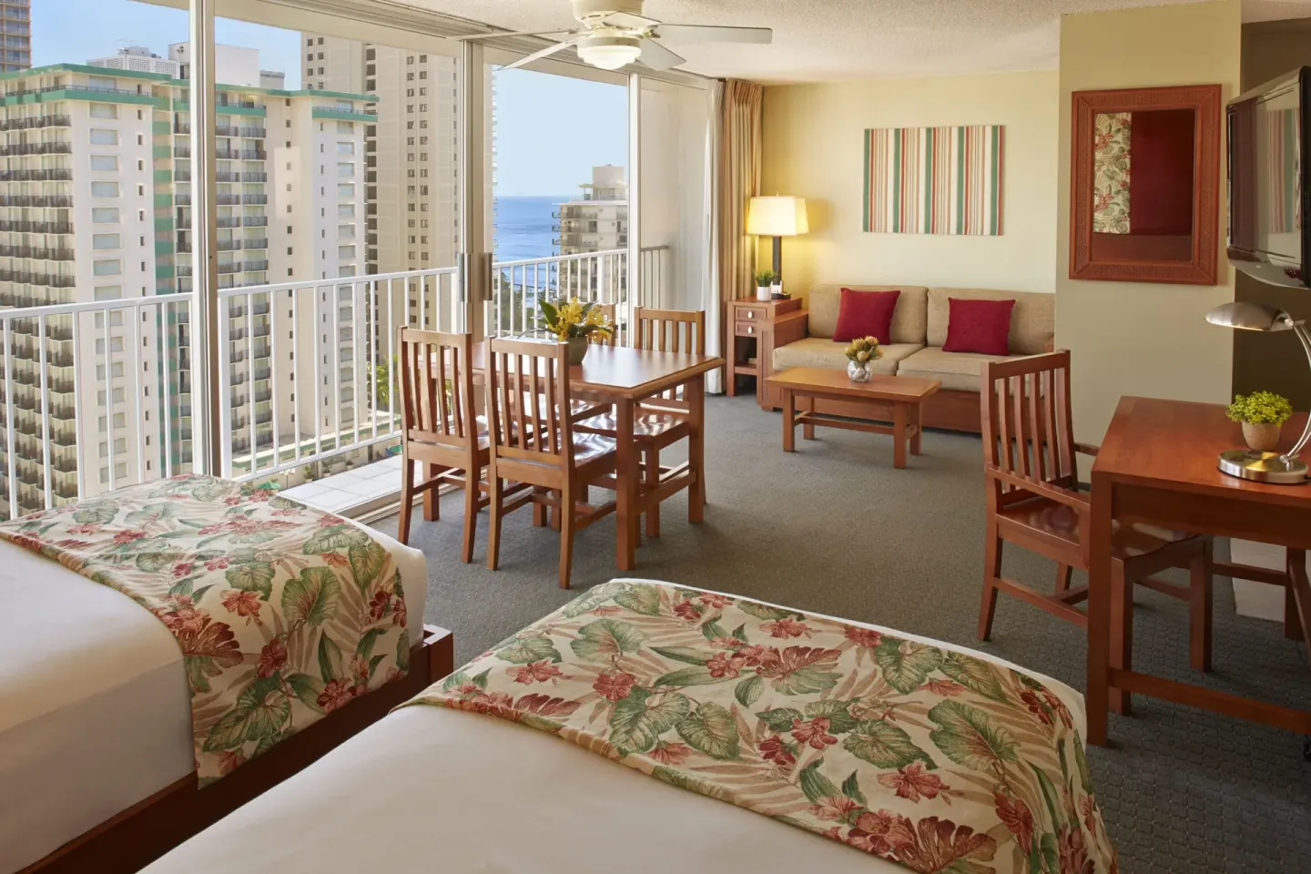 Studio Suite with two beds, dining table, sofa, and balcony view at Pacific Monarch Hotel.