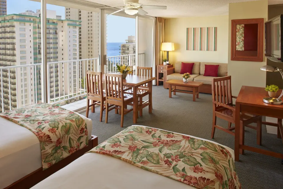 Studio Suite with two beds, dining table, sofa, and balcony view at Pacific Monarch Hotel.